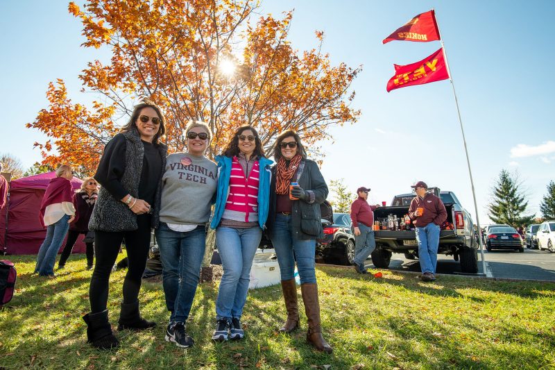 Four students posing outside a football tailgate event